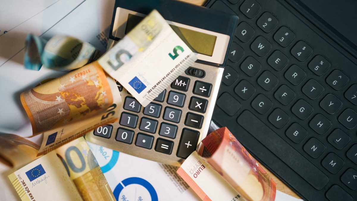 Billets en euros, calculatrice et graphiques de repartition salariale sur un bureau