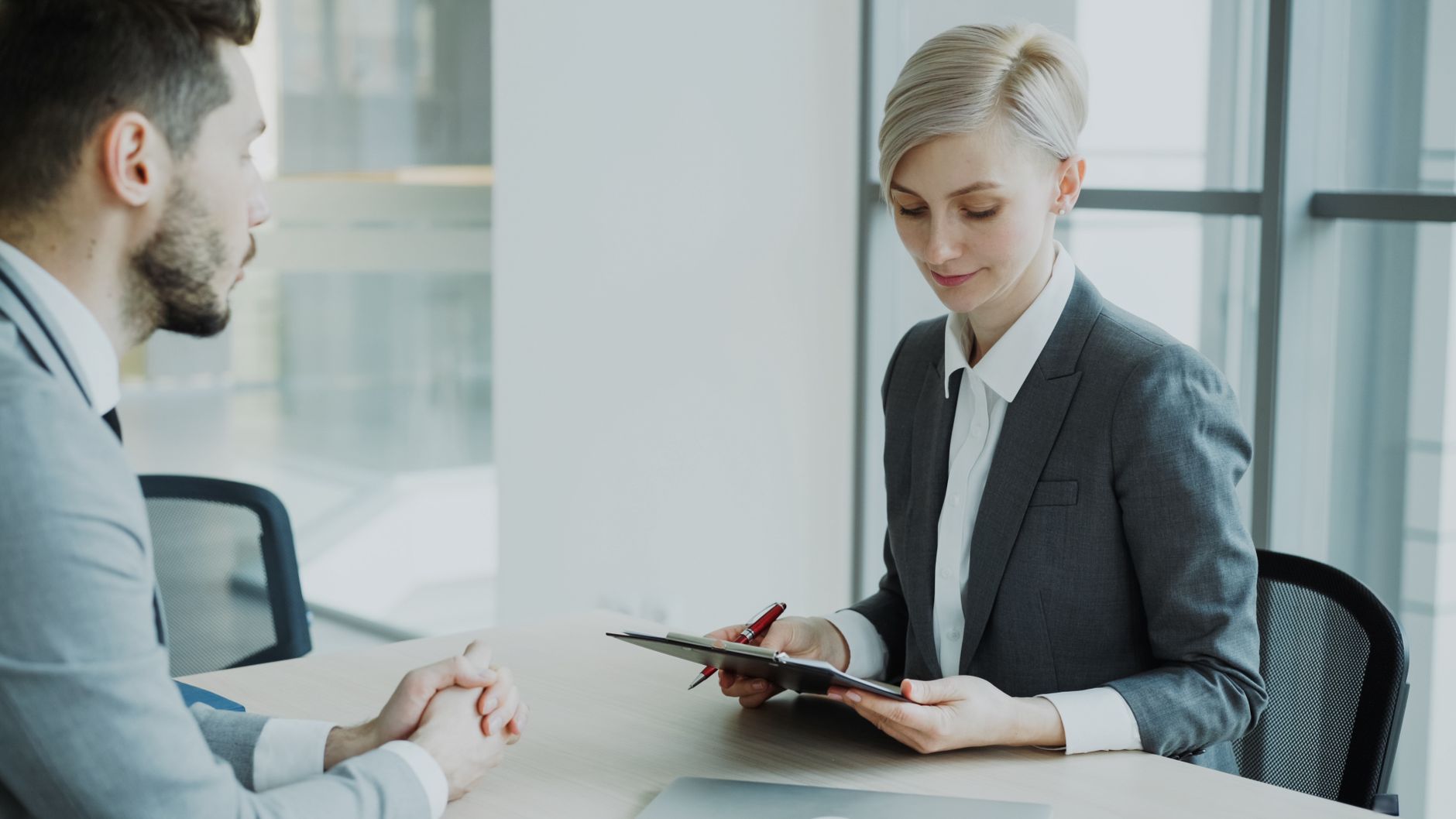 entretien de recrutement entre un candidat et une responsable RH dans un bureau, prise de notes sur tablette