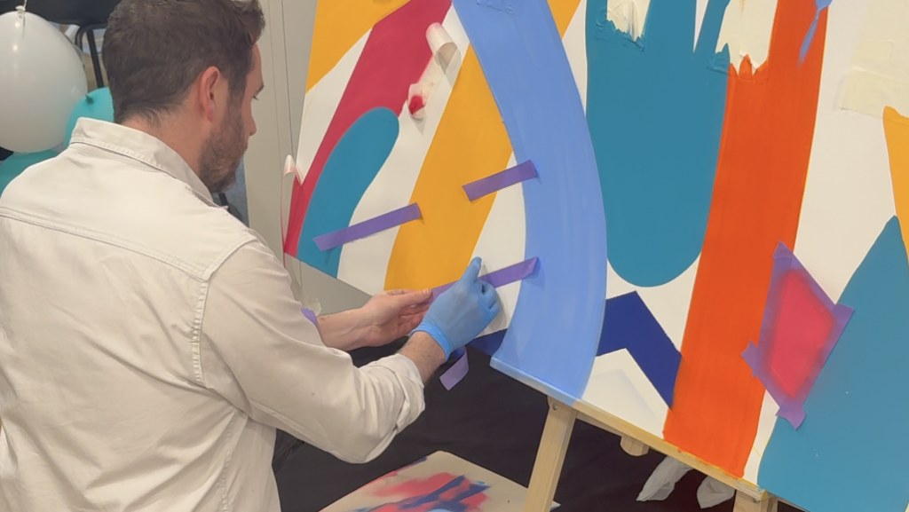 Un collaborateur peint lui-même une partie de la toile lors d'un live painting participatif